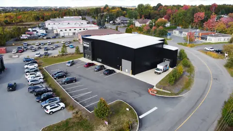 Aerial view in autumn of the black-clad ReStore building with its parking apron, a delivery truck at the loading door, and the surrounding industrial area