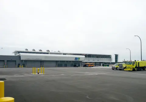 The Airside Operations building seen across the airfield apron, with YVR signage and yellow airport emergency vehicles parked in front