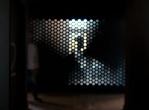 Light passing through the perforated screen wall in a dark corridor