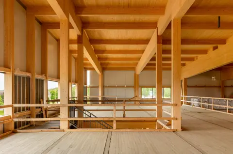 Mezzanine level with exposed timber beams and a guardrail looking over the warehouse floor